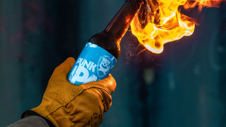 A BrewDog Punk IPA bottle reimagined as a flaming Molokai cocktail, showcasing rebellious creativity and striking visual impact.