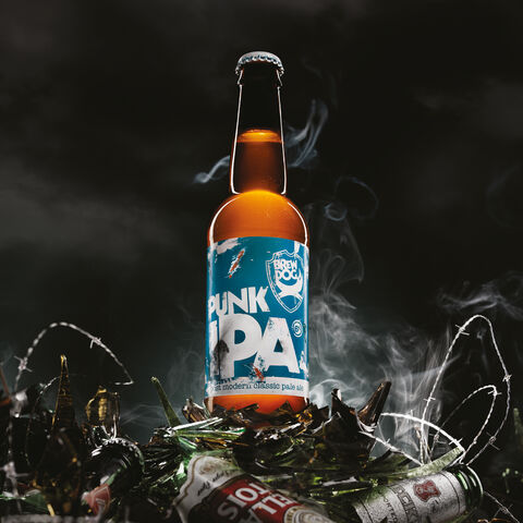 A Punk IPA beer bottle standing triumphantly on a pile of smashed Stella Artois and Beck's beer bottles.